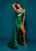 Green satin column shaped dress with three angled straps and ruching with a high slit