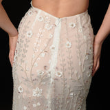 Ethereal ivory and white gown with floral embellishments and a dramatic thigh-high slit.