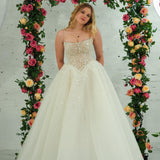 white wedding ballgown featuring a straight neckline, delicate beaded straps, sheer sparkling bodice, basque waistline, and corset back.