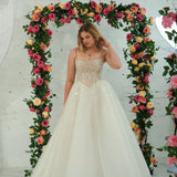 white wedding ballgown featuring a straight neckline, delicate beaded straps, sheer sparkling bodice, basque waistline, and corset back.