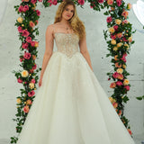 white wedding ballgown featuring a straight neckline, delicate beaded straps, sheer sparkling bodice, basque waistline, and corset back.