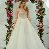 white wedding ballgown featuring a straight neckline, delicate beaded straps, sheer sparkling bodice, basque waistline, and corset back.