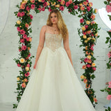 white wedding ballgown featuring a straight neckline, delicate beaded straps, sheer sparkling bodice, basque waistline, and corset back.