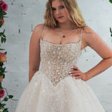 white wedding ballgown featuring a straight neckline, delicate beaded straps, sheer sparkling bodice, basque waistline, and corset back.