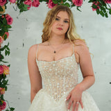 white wedding ballgown featuring a straight neckline, delicate beaded straps, sheer sparkling bodice, basque waistline, and corset back.