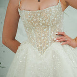 white wedding ballgown featuring a straight neckline, delicate beaded straps, sheer sparkling bodice, basque waistline, and corset back.