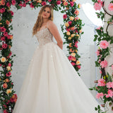 white wedding ballgown featuring a straight neckline, delicate beaded straps, sheer sparkling bodice, basque waistline, and corset back.