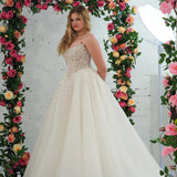 white wedding ballgown featuring a straight neckline, delicate beaded straps, sheer sparkling bodice, basque waistline, and corset back.