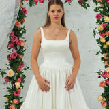 white wedding ballgown with straight neckline, basque waist, corset back, and layered skirt.