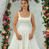 white wedding ballgown with straight neckline, basque waist, corset back, and layered skirt.