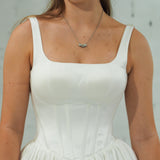 white wedding ballgown with straight neckline, basque waist, corset back, and layered skirt.