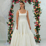 white wedding ballgown with straight neckline, basque waist, corset back, and layered skirt.