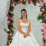 white wedding ballgown with straight neckline, basque waist, corset back, and layered skirt for hire
