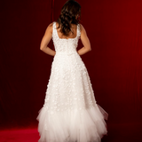 Romantic A-line gown with 3D florals, glittered mesh, and soft tulle layers.