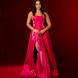 A hot pink satin formal gown with a straight neckline, basque waist, corset back, and thigh-high slit.