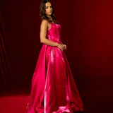 A hot pink satin formal gown with a straight neckline, basque waist, corset back, and thigh-high slit.