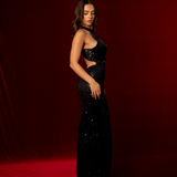A black formal mermaid gown with halter neckline, open low back, and sparkling beaded fabric.