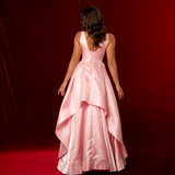 A baby pink formal A-line gown with plunging V neckline, thick straps, corset back, and dramatic liquid taffeta ruffled skirt.