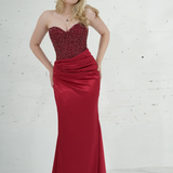 Dazzling red mermaid gown featuring a beaded corset bodice, thigh-high slit, and elegant train.