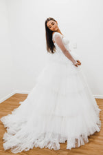 White wedding dress with a bushier top and a bushier puffy layered skirt.